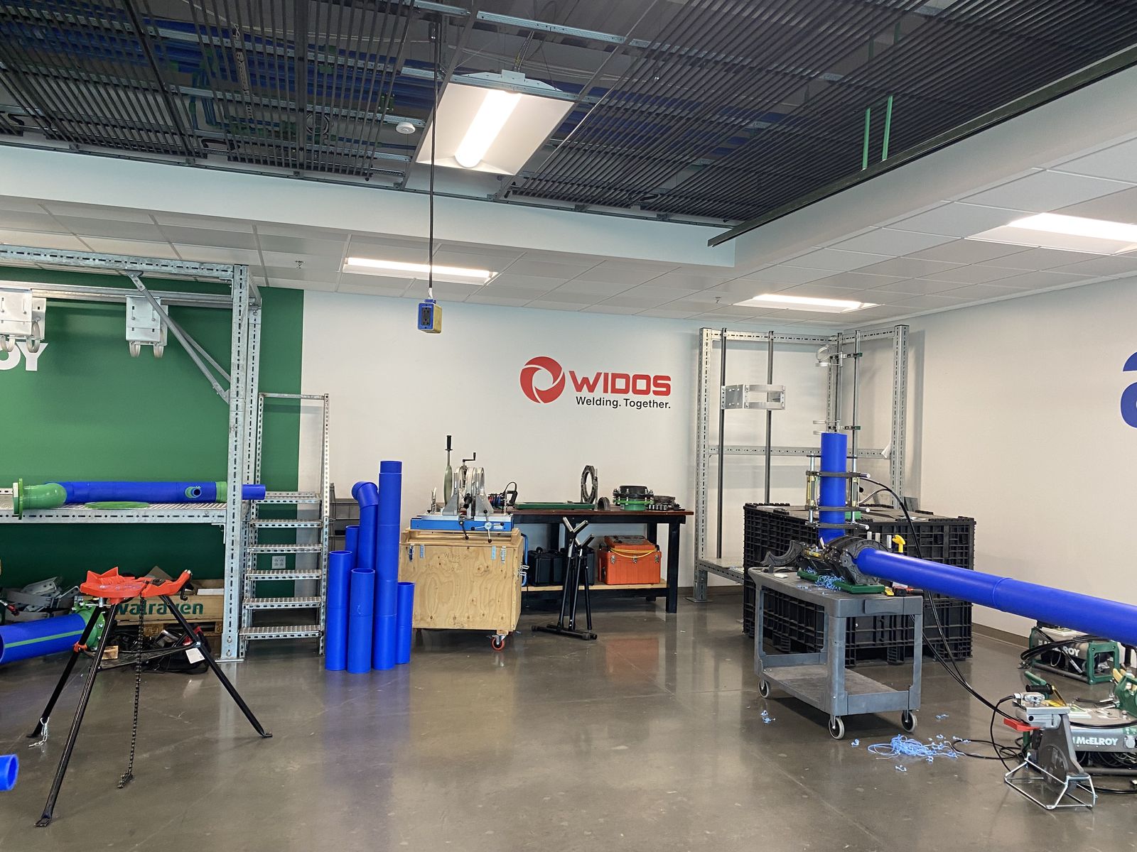 Pipe-fusion training shop with blue PP-R pipe on stands and fusion machines