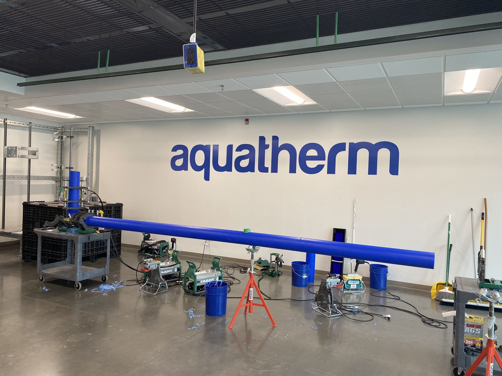 Aquatherm facility interior with wall logo, blue PP-R pipe and fusion equipment
