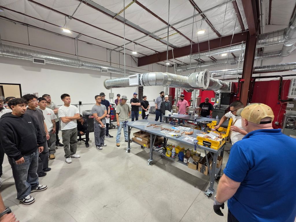 Rob Warnell, back to camera, leading a hands-on press-fitting class for a room of trainees